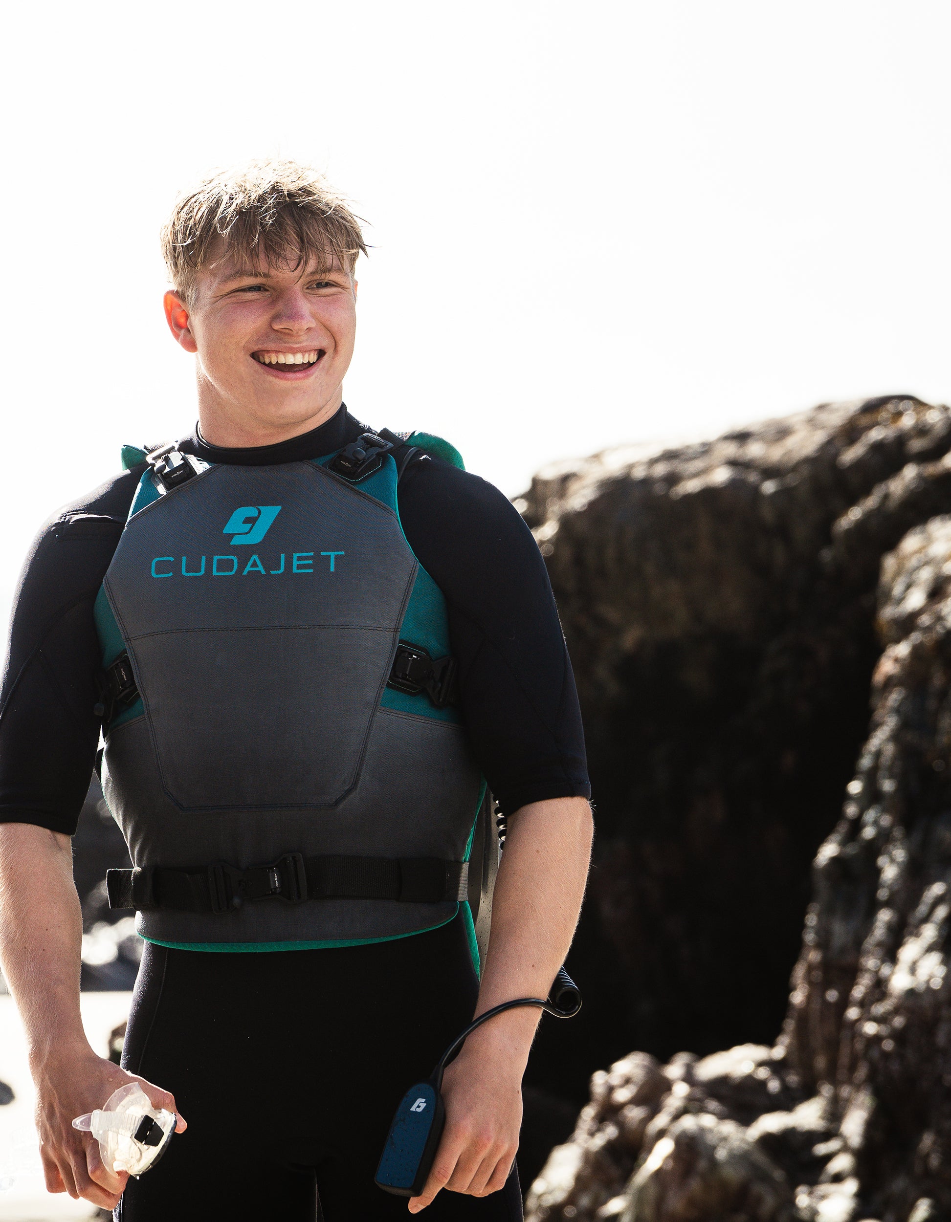 Person wearing a Cudajet vest standing on a rocky beach