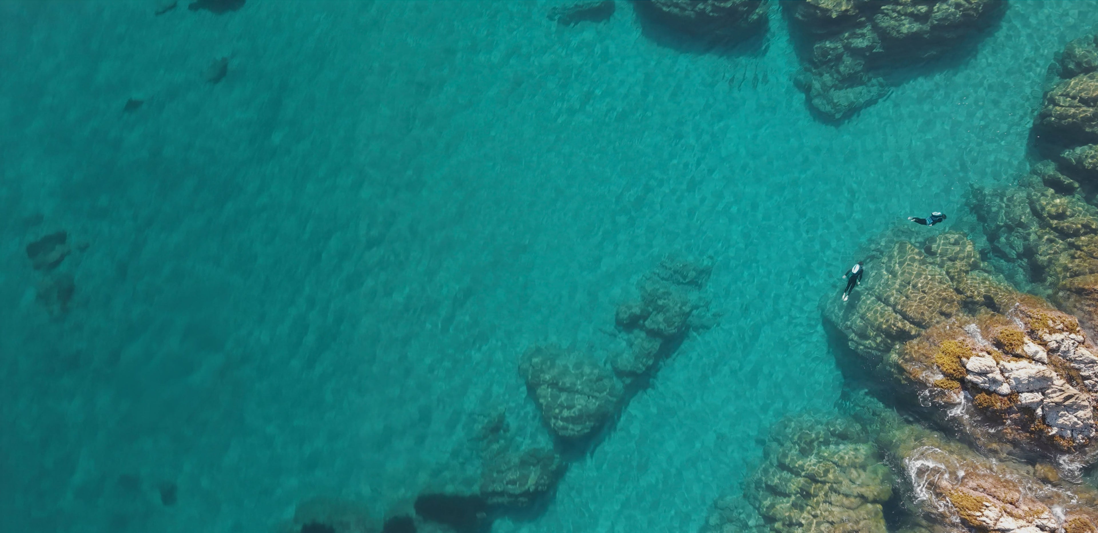 People underwater jetpacking in clear blue water